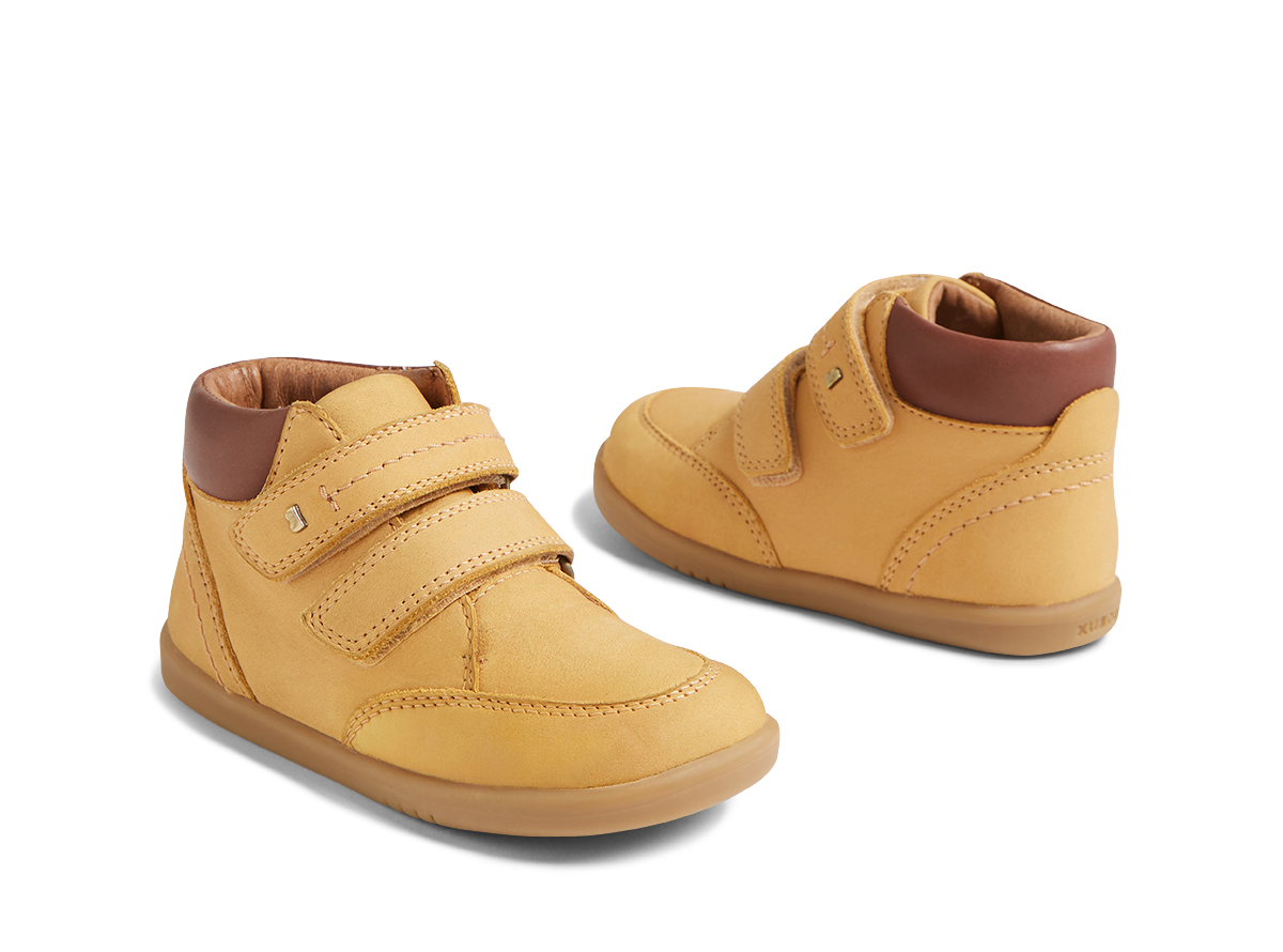 Pair of yellow children's shoes with brown soles on a white background