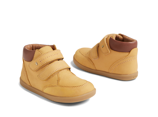 Pair of yellow children's shoes with brown soles on a white background